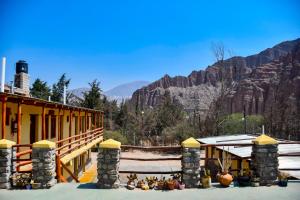 a building with snow on the ground with mountains in the background at Tilcara Rustica Hostel in Tilcara