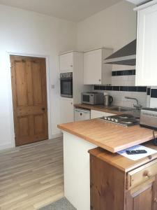 cocina con armarios blancos y encimera de madera en Charming 1-Bedroom Apartment near South Downs, en Hailsham