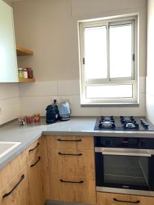 a kitchen with a stove and a window at מעבר לאופק in Yeroẖam