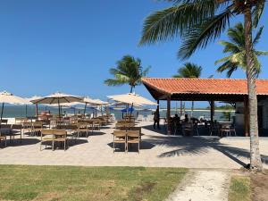 a restaurant on the beach with tables and umbrellas at Catamaran Praia Chalés in Igarassu