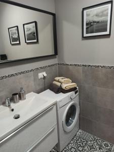een badkamer met een wasmachine en een wastafel bij MD Apartament Lewandowskiego in Szczecin