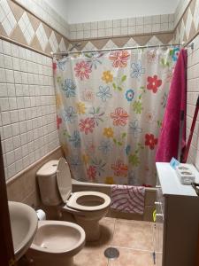 a bathroom with a toilet and a shower curtain with flowers at El Hoyo in Frontera