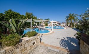 a swimming pool in a resort with palm trees at Isida Hotel Agia Marina in Agia Marina Nea Kydonias