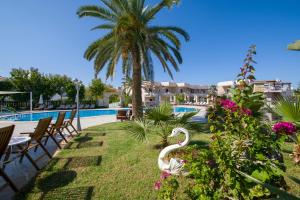 a resort with a swimming pool and a palm tree at Isida Hotel Agia Marina in Agia Marina Nea Kydonias