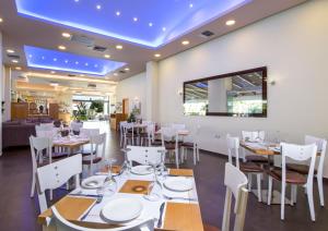 a restaurant with white tables and chairs and a blue ceiling at Isida Hotel Agia Marina in Agia Marina Nea Kydonias