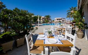 a table and chairs with a table and a pool at Isida Hotel Agia Marina in Agia Marina Nea Kydonias