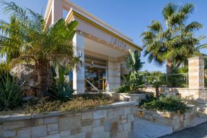 a building with palm trees in front of it at Isida Hotel Agia Marina in Agia Marina Nea Kydonias