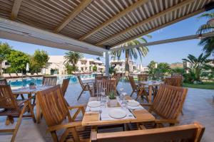 a patio with tables and chairs and a pool at Isida Hotel Agia Marina in Agia Marina Nea Kydonias