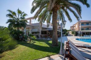 a house with a palm tree and a swimming pool at Isida Hotel Agia Marina in Agia Marina Nea Kydonias