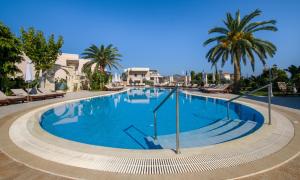 a large swimming pool with palm trees in a resort at Isida Hotel Agia Marina in Agia Marina Nea Kydonias