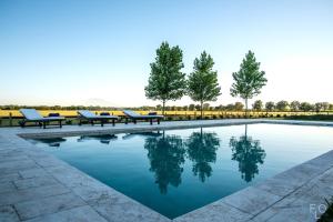 a pool with benches and trees in a park at Estancia La Sofia in San Andrés de Giles