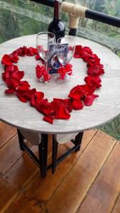 a table with a heart of red roses and wine glasses at Glamping Casa Viva in Pereira