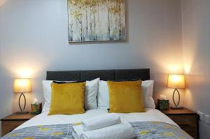 ein Schlafzimmer mit einem Bett mit gelben Kissen und zwei Lampen in der Unterkunft Delight Marvel-Wexford Place, Maidstone in Maidstone