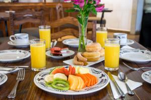 a wooden table with a plate of fruit and orange juice at Hotel La Casona 30 in San Miguel de Allende