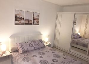 a white bedroom with a bed and a mirror at Apartman Dunja in Prijedor