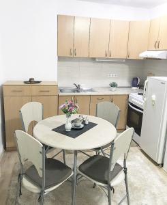 a kitchen with a table and chairs and a white refrigerator at Apartman Dunja in Prijedor