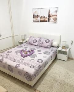 a bedroom with a bed with a purple and white comforter at Apartman Dunja in Prijedor