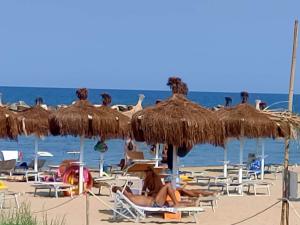 eine Gruppe von Menschen, die am Strand unter Sonnenschirmen auf Stühlen liegen in der Unterkunft Villa Carol "Ortensia1" "Ortensia 2" in Tollo