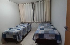 two beds sitting in a room with a window at Apto confortável Grand Reserva Casa da Madeira! in Caldas Novas