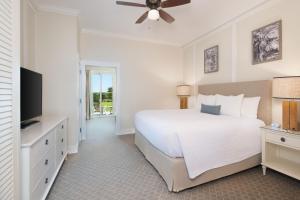 1 dormitorio con 1 cama blanca y TV de pantalla plana en Jekyll Ocean Club Resort en Jekyll Island