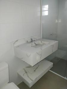 La salle de bains blanche est pourvue d'un lavabo et de toilettes. dans l'établissement Casa para hospedagem temporário, à Joinville