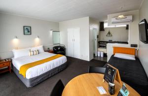 a hotel room with a large bed and a table at Aura Accommodation in Rotorua