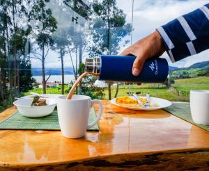 a person pouring coffee into a cup on a table at Glamping Cristal in Guatavita