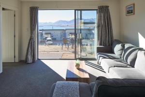 ein Wohnzimmer mit einem Sofa und Meerblick in der Unterkunft Alpine View Apartment 3 - Tekapo in Lake Tekapo