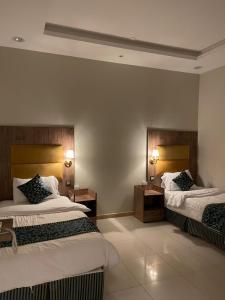 a hotel room with two beds and two lamps at مقر الفخامة in Abha