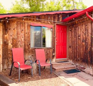 two chairs sitting outside of a house with a red door at Foot of the Mountain Motel in Boulder