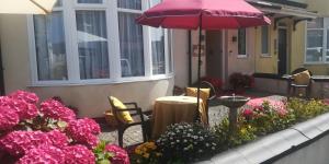 a patio with a table and umbrella and flowers at Northdene Theatre Hotel in Blackpool