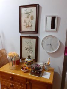 uma mesa com um relógio e quadros na parede em Damiani House em Marsala