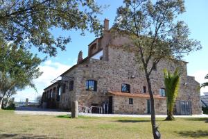 un viejo edificio de piedra con un árbol delante de él en Rincón del Abade, en Encinasola