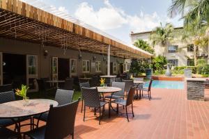 eine Terrasse mit Tischen und Stühlen und einem Pool in der Unterkunft ANEW Hotel Capital Pretoria in Pretoria