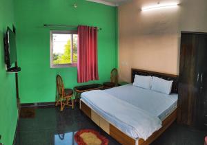 een slaapkamer met een bed en een groene muur bij Nandini Homestay in Dehradun