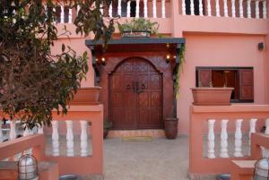 różowy dom z drewnianymi drzwiami i schodami w obiekcie Résidence Fanti w mieście Sidi Binnzarene