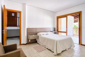 una camera da letto bianca con un letto e una sedia di Cobertura - Praia Grande, Ubatuba a Ubatuba Altre 60 foto