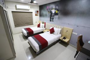 a bedroom with two beds and a painting on the wall at The Butterfly Luxury Serviced Apartments in Visakhapatnam