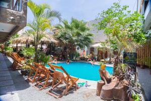 a swimming pool with chairs and people in a resort at Banana's Adventure Hostel in Ica