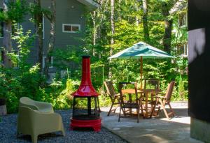 un patio con mesa, sillas y sombrilla en Mojo Lodge Hakuba en Hakuba