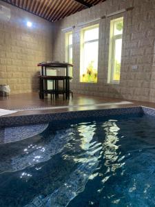 a swimming pool in a house with a table and windows at Oriental Nights Rest House in Al Wāşil