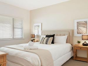 a bedroom with a large white bed with a towel on it at Ocean Blue Apartment One in Currarong