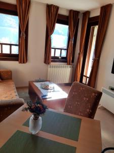 salon ze stołem, krzesłami i oknami w obiekcie Relax Apartman w mieście Fojnica