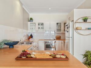 a kitchen with a cutting board with cheese and wine glasses at Ocean Blue Apartment Two in Currarong
