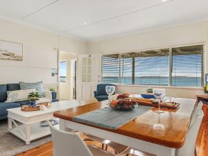 uma sala de estar com uma mesa e cadeiras e um sofá em Ocean Blue Apartment Two em Currarong