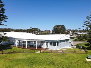 a white house with a white roof and a yard at Ocean Blue Apartment Two in Currarong