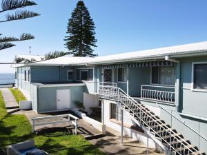 a house with a staircase in front of the ocean at Ocean Blue Apartment Four in Currarong