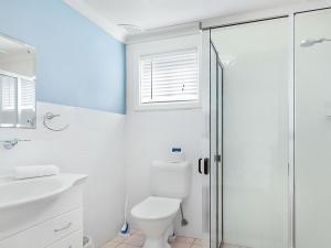 a white bathroom with a toilet and a shower at Ocean Blue Apartment Five in Currarong