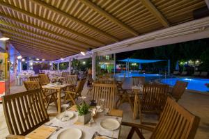 a restaurant with tables and chairs and a pool at Isida Hotel Agia Marina in Agia Marina Nea Kydonias