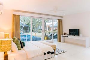 sypialnia z dużym łóżkiem i telewizorem w obiekcie CassaMia Bali - Spacious Luxury 5 Bedroom Villa, 100m from Beach with Butler w mieście Jimbaran